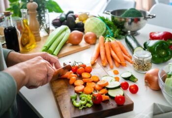 Someone prepares a healthy meal full of vegetables and healthy foods